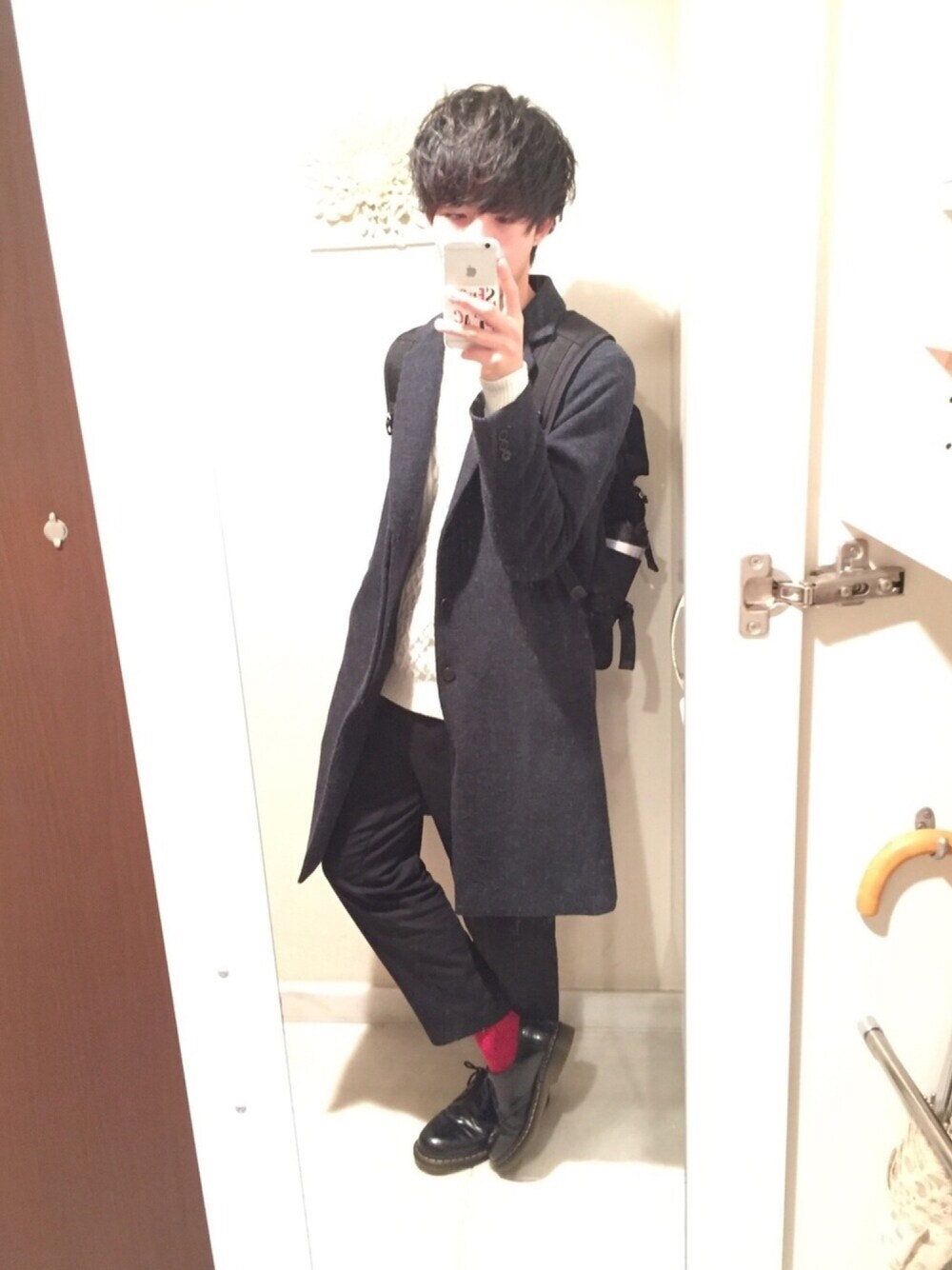 ブルー系のチェスターコート、ホワイト系のニット/セーター、ブラック系のその他パンツを着用したメンズの冬コーディネートの1枚目の写真