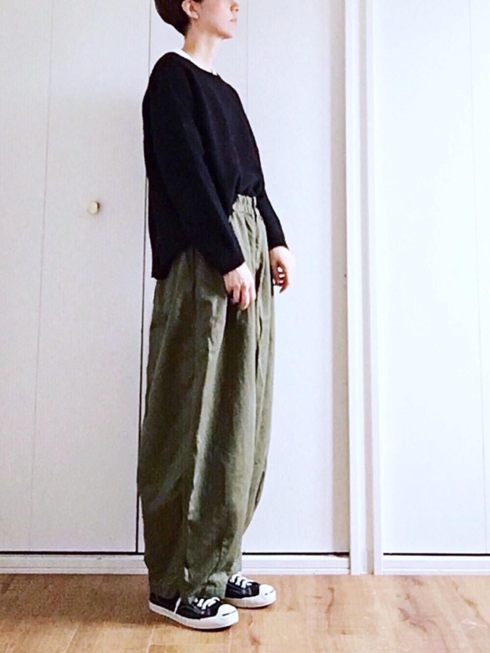 グリーン系のパンツ、ブラック系のニット/セーターを着用したレディースの秋コーディネートの1枚目の写真