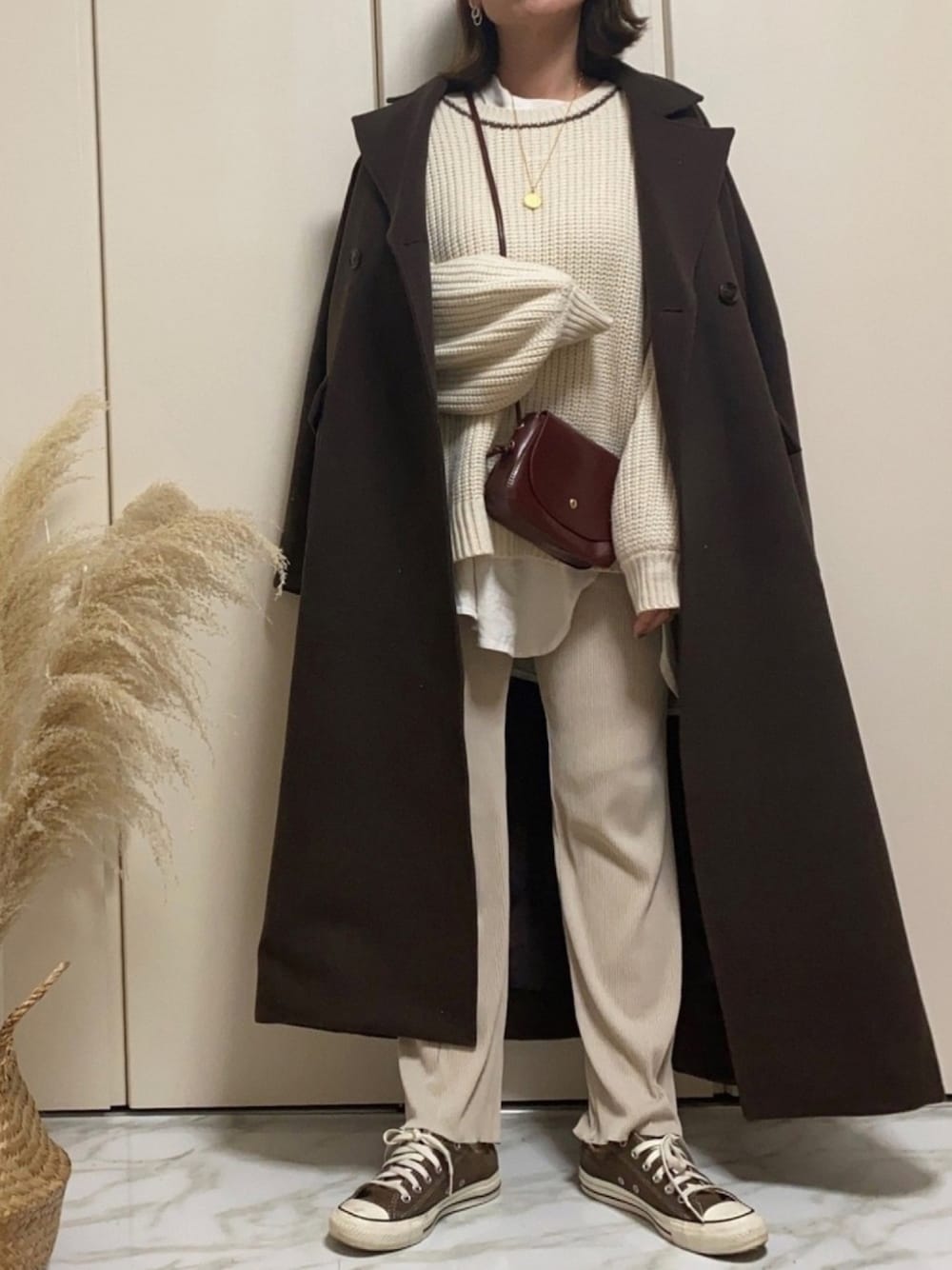 ベージュ系のパンツ、ベージュ系のニット/セーター、ブラウン系のチェスターコートを着用したレディースの冬コーディネートの1枚目の写真