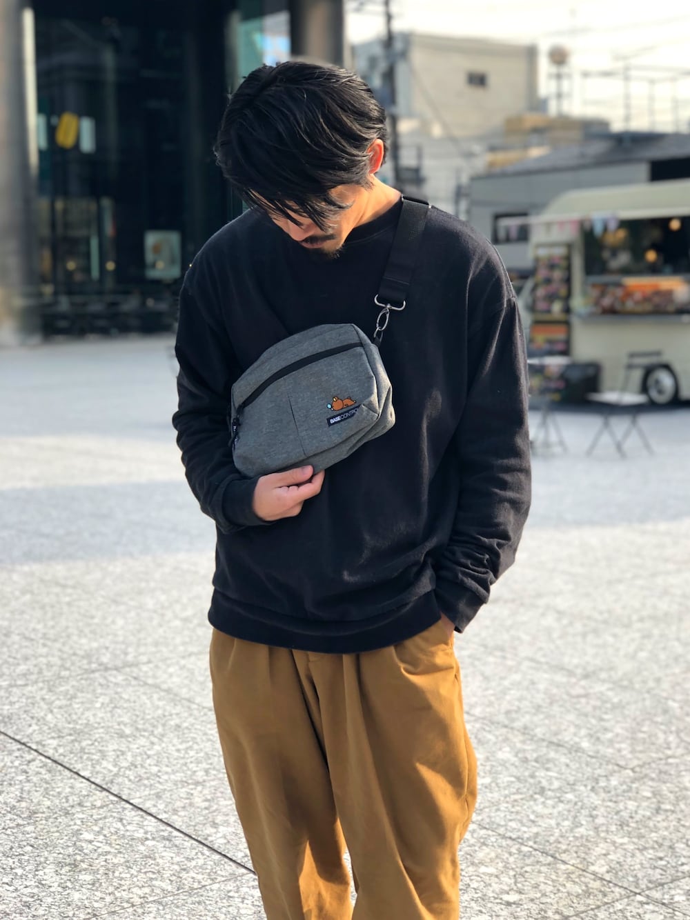 グレー系のショルダーバッグ、イエロー系のスラックス、ブラック系のTシャツ/カットソーを着用したメンズの冬コーディネートの1枚目の写真