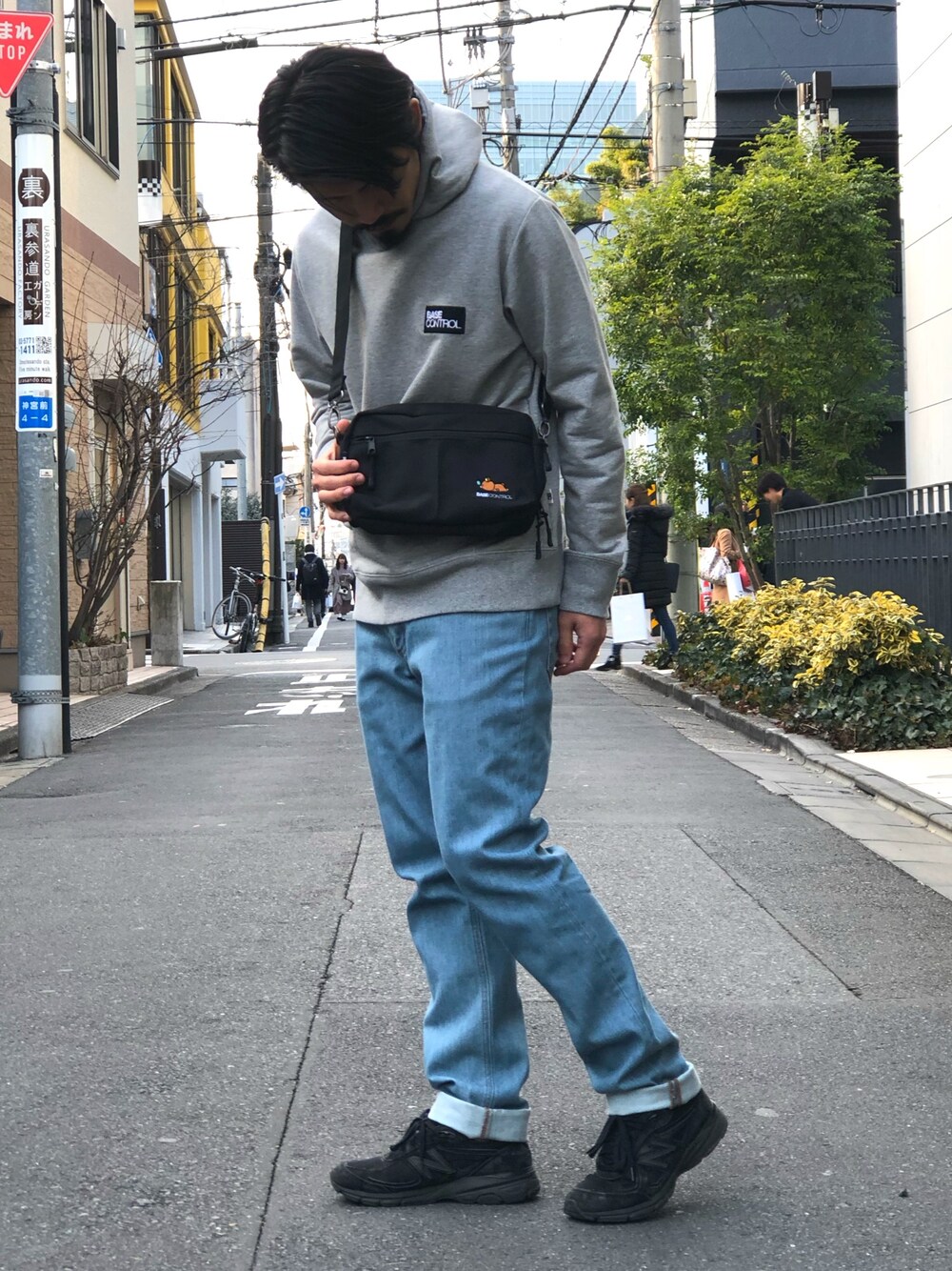 ブラック系のショルダーバッグ、グレー系のパーカー、ブルー系のデニムパンツを着用したメンズの冬コーディネートの1枚目の写真