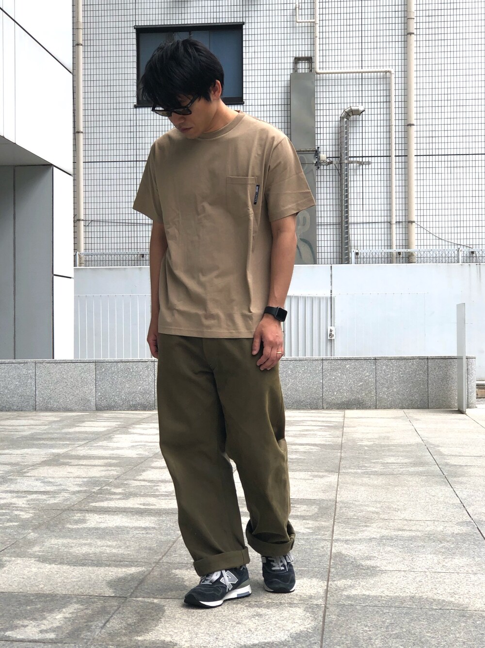 ベージュ系のTシャツ/カットソー、グリーン系のパンツ、ブルー系のスニーカーを着用したメンズの春コーディネートの1枚目の写真
