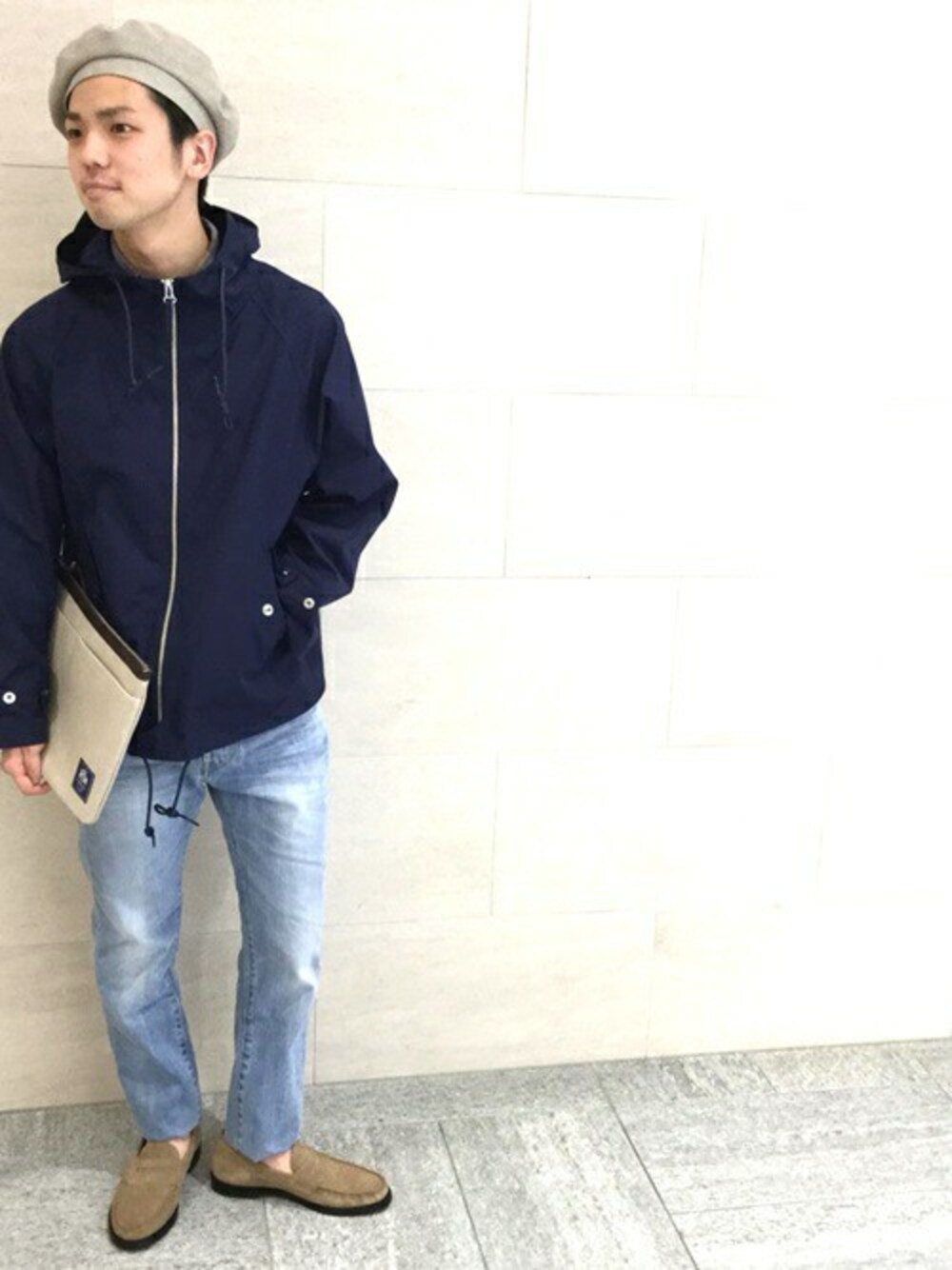 ブルー系のデニムパンツ、ベージュ系のクラッチバッグを着用したメンズの春コーディネートの1枚目の写真