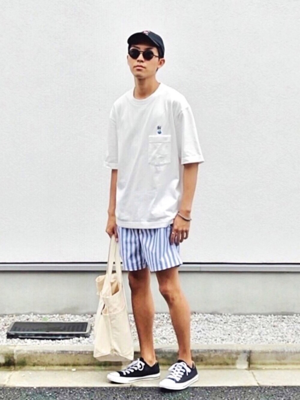 ホワイト系のTシャツ/カットソー、グレー系のパンツ、ブラック系のスニーカーを着用したメンズの夏コーディネートの1枚目の写真