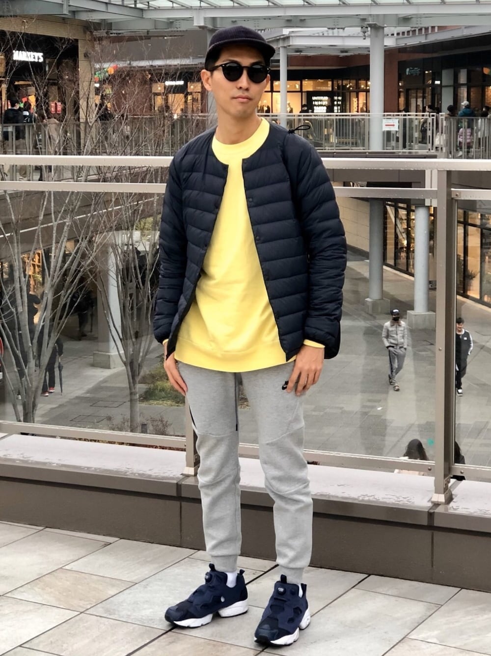 ブルー系のダウンジャケット/コート、イエロー系のTシャツ/カットソー、グレー系のスウェットパンツを着用したメンズの冬コーディネートの1枚目の写真
