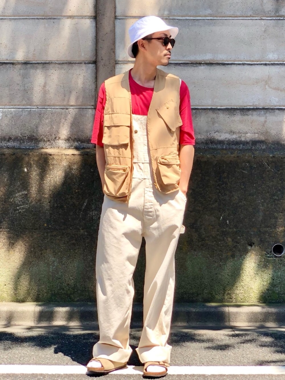 レッド系のTシャツ/カットソー、ベージュ系のベスト、ベージュ系のサロペット/オーバーオールを着用したメンズの夏コーディネートの1枚目の写真