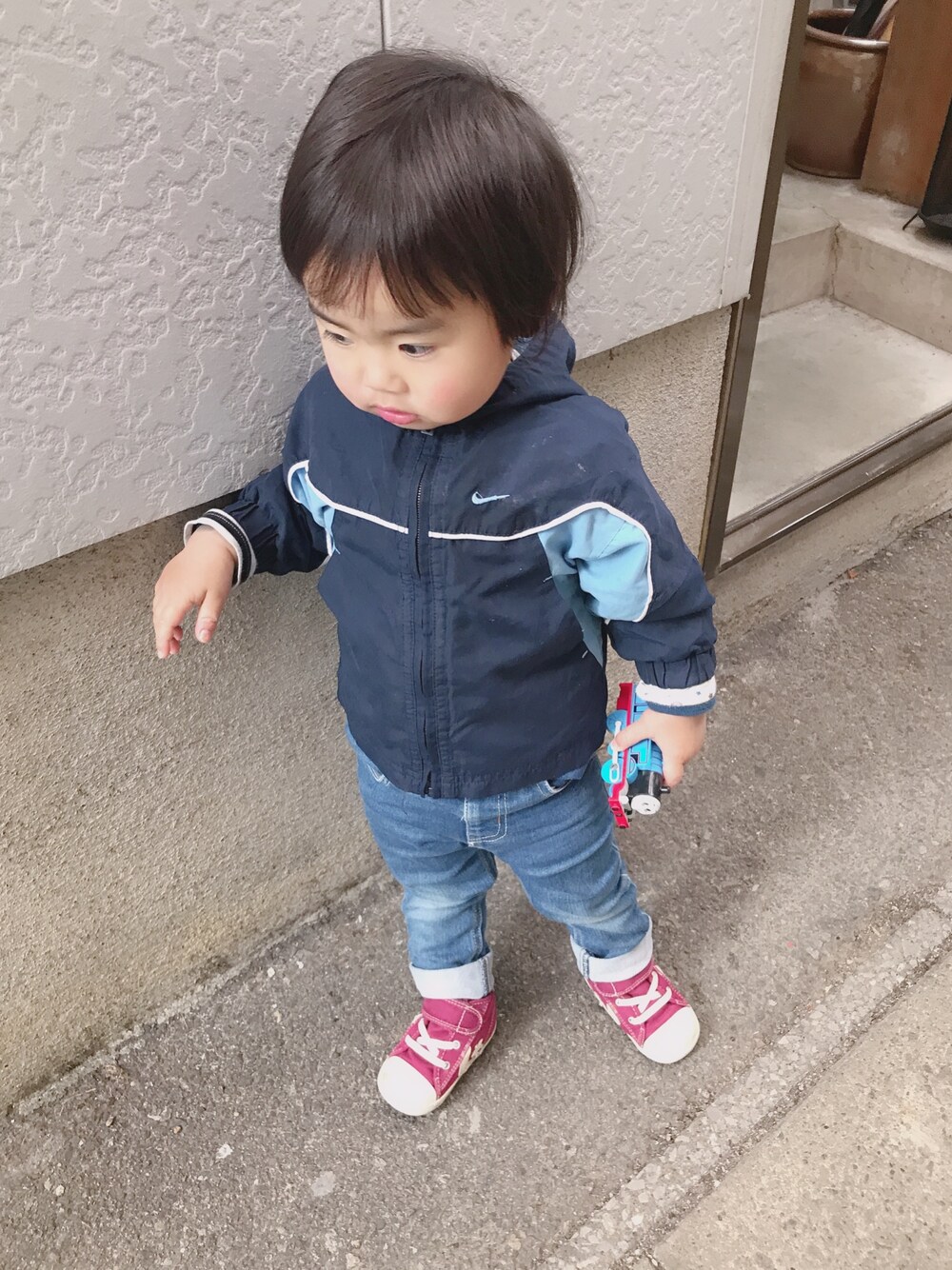 ブルー系のナイロンジャケット、ブルー系のデニムパンツ、レッド系のスニーカーを着用したキッズの秋コーディネートの1枚目の写真