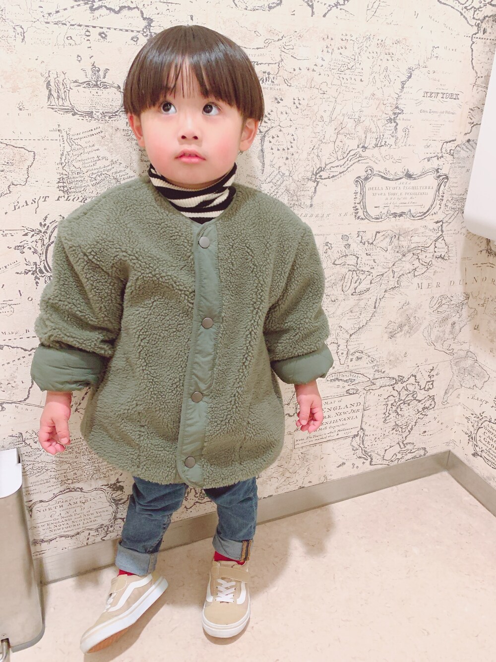 グリーン系のジャケット/アウター、ブラック系のニット/セーター、ブルー系のデニムパンツを着用したキッズの冬コーディネートの1枚目の写真