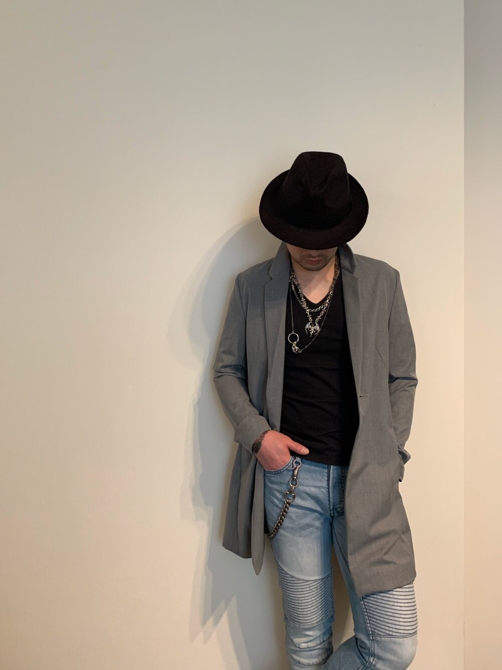 グレー系のチェスターコート、ブルー系のデニムパンツ、シルバー系のネックレスを着用したメンズの春コーディネートの1枚目の写真