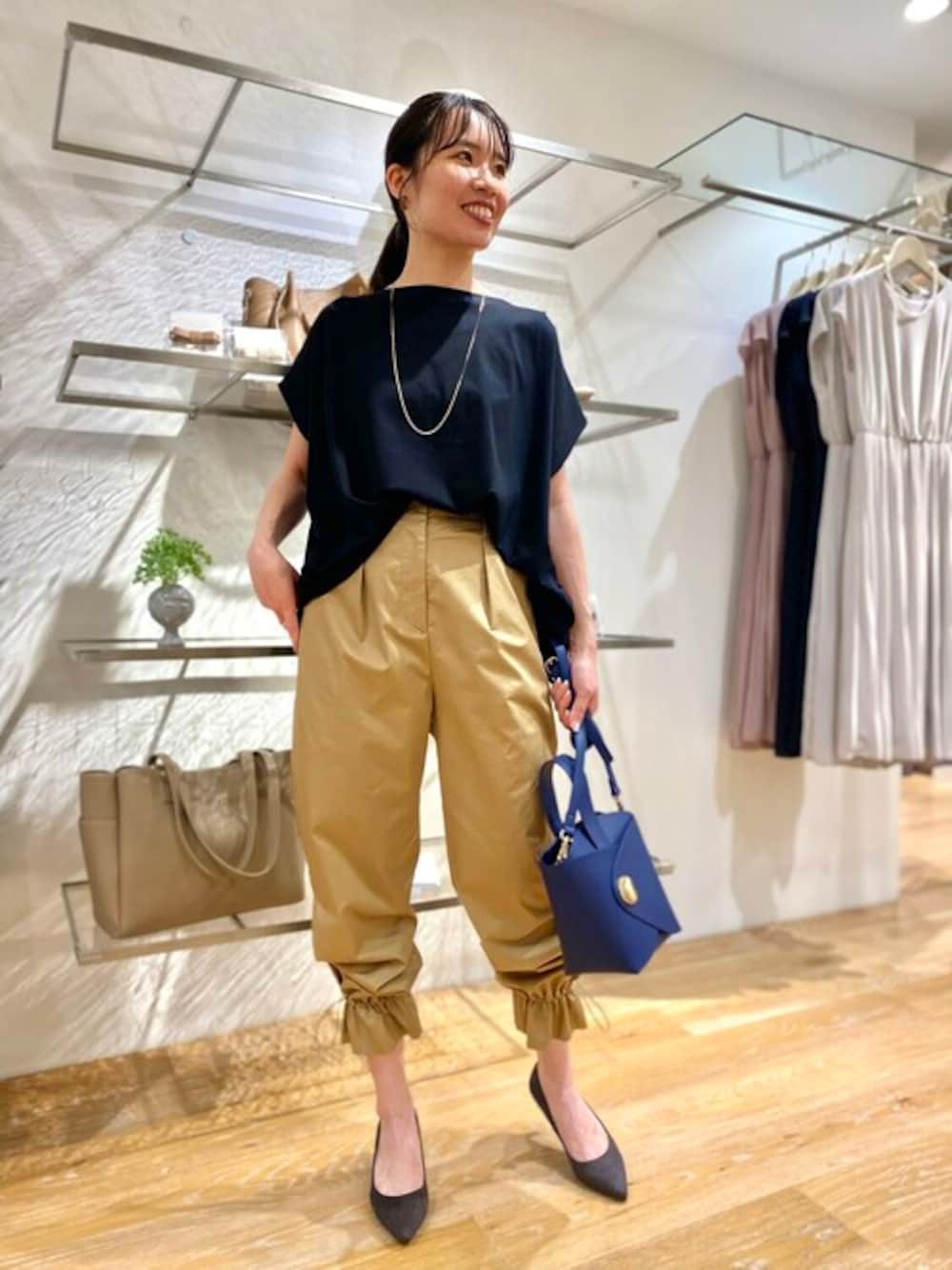 ブラック系のTシャツ/カットソー、ベージュ系のその他パンツ、ブルー系のハンドバッグを着用したレディースの夏コーディネートの1枚目の写真