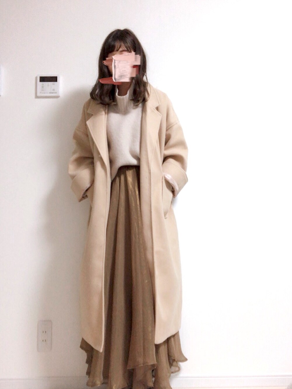 ベージュ系のニット/セーター、ベージュ系のチェスターコート、ブラウン系のスカートを着用したレディースの冬コーディネートの1枚目の写真