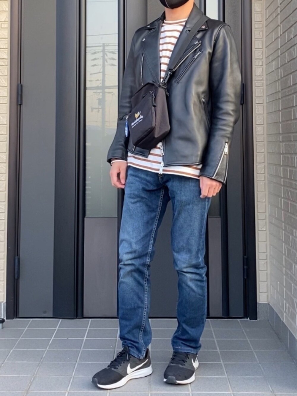 ブラック系のライダースジャケット、ブラウン系のTシャツ/カットソー、ブラック系のスニーカーを着用したメンズの秋コーディネートの1枚目の写真