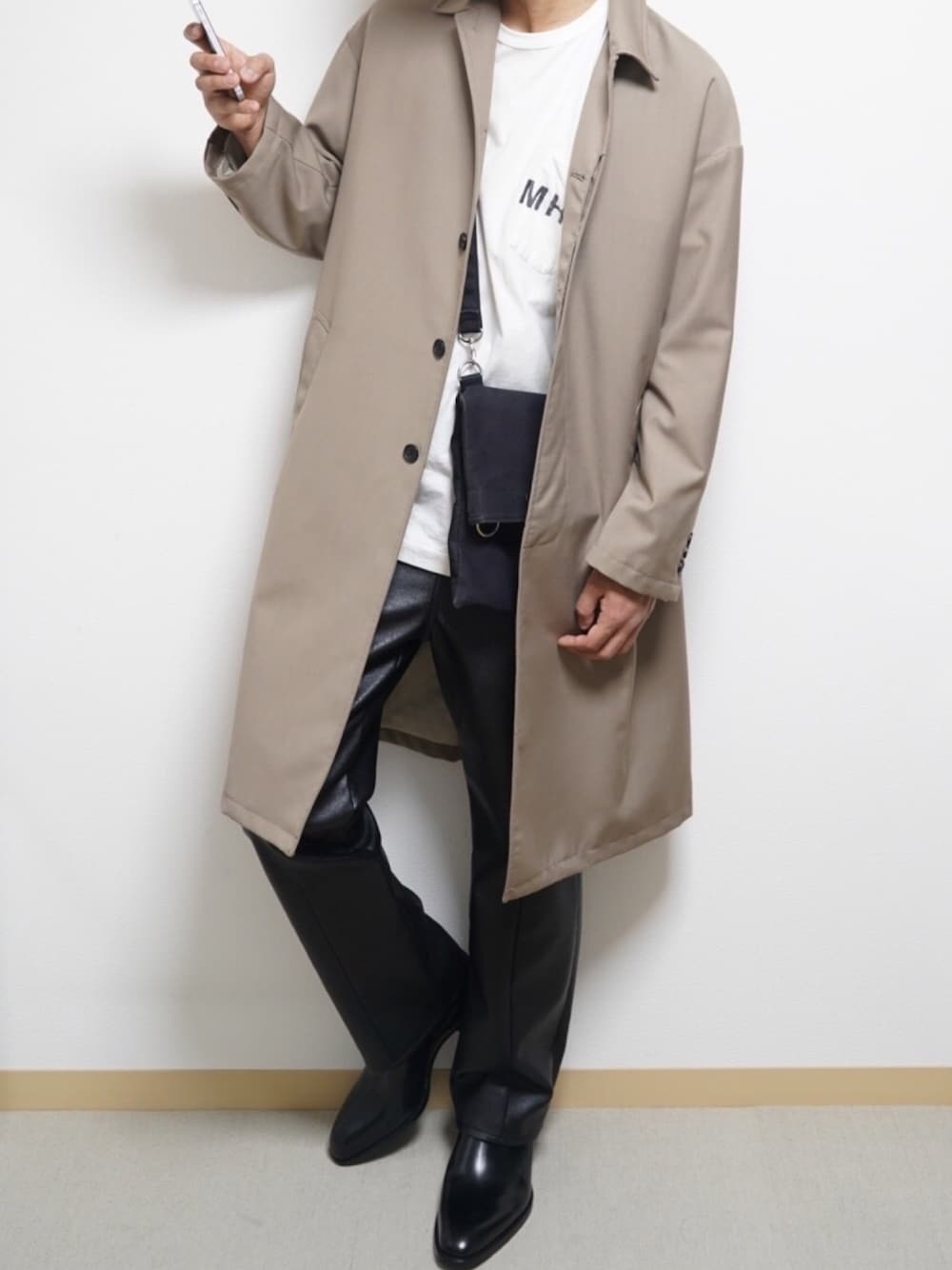 「春夏コーデ、春コーデ、おうちファッション、きれいめカジュアル、オーバーサイズ、ステンカラーコート、ロゴT、レザーパンツ、ヒールブーツ、サコッシュ」｜「MHL.のMHL.×URBAN RESEARCH　別注PRINTED T-SHIRTS（Tシャツ/カットソー、ホワイト系）」を使った、れんさん（メンズ・172cm）の春コーディネートの1枚目の写真
