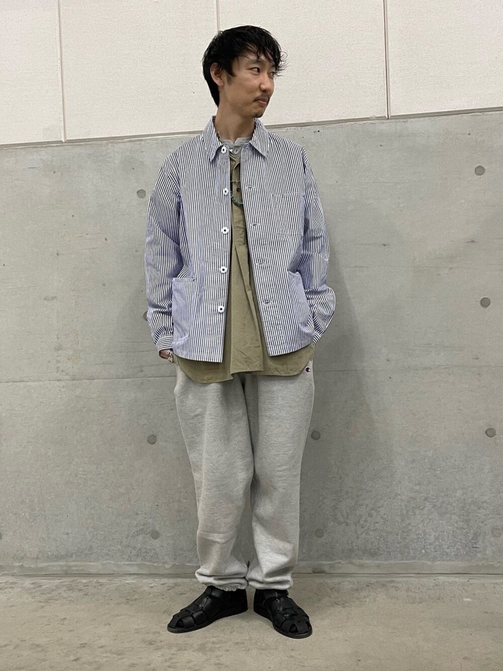 ホワイト系のカバーオール、グレー系のスウェットパンツ、ブラック系のサンダルを着用したメンズの春コーディネートの1枚目の写真