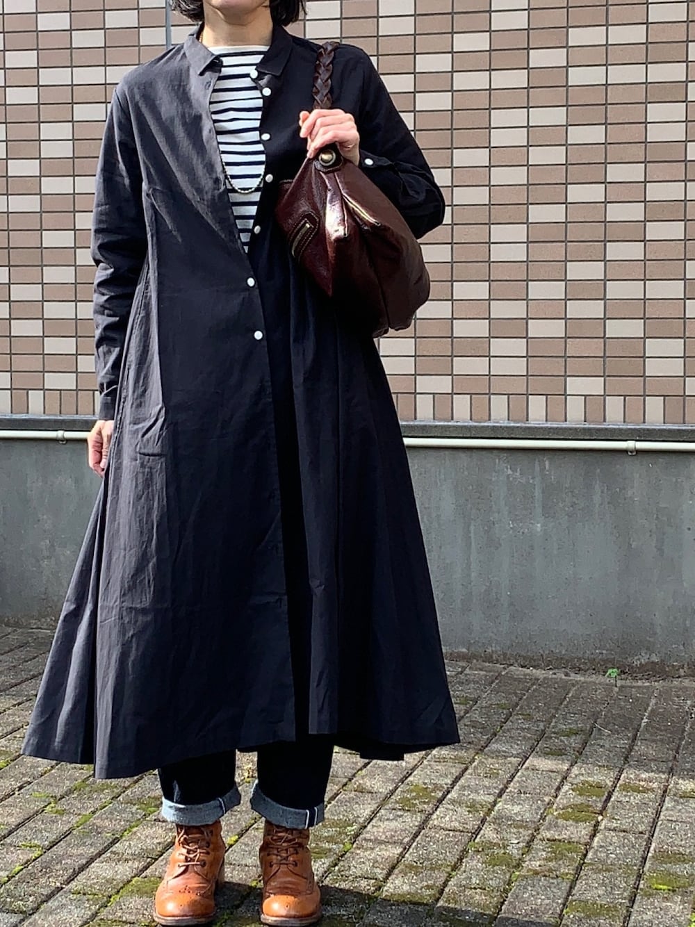 ブラック系のシャツワンピース、ホワイト系のTシャツ/カットソー、ブラウン系のバッグを着用したレディースの秋コーディネートの1枚目の写真