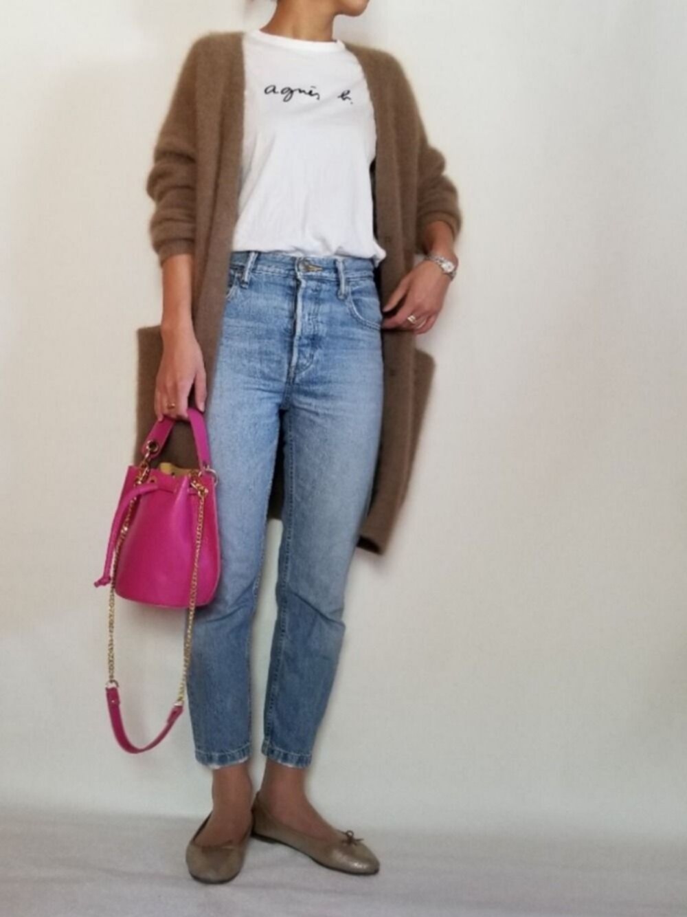 ブラウン系のカーディガン/ボレロ、ピンク系のショルダーバッグ、ブルー系のデニムパンツを着用したレディースの冬コーディネートの1枚目の写真