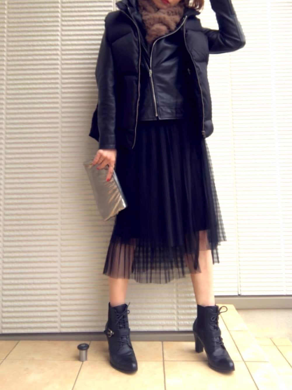 ブラック系のダウンベスト、ブラック系のライダースジャケット、シルバー系のクラッチバッグを着用したレディースの冬コーディネートの1枚目の写真