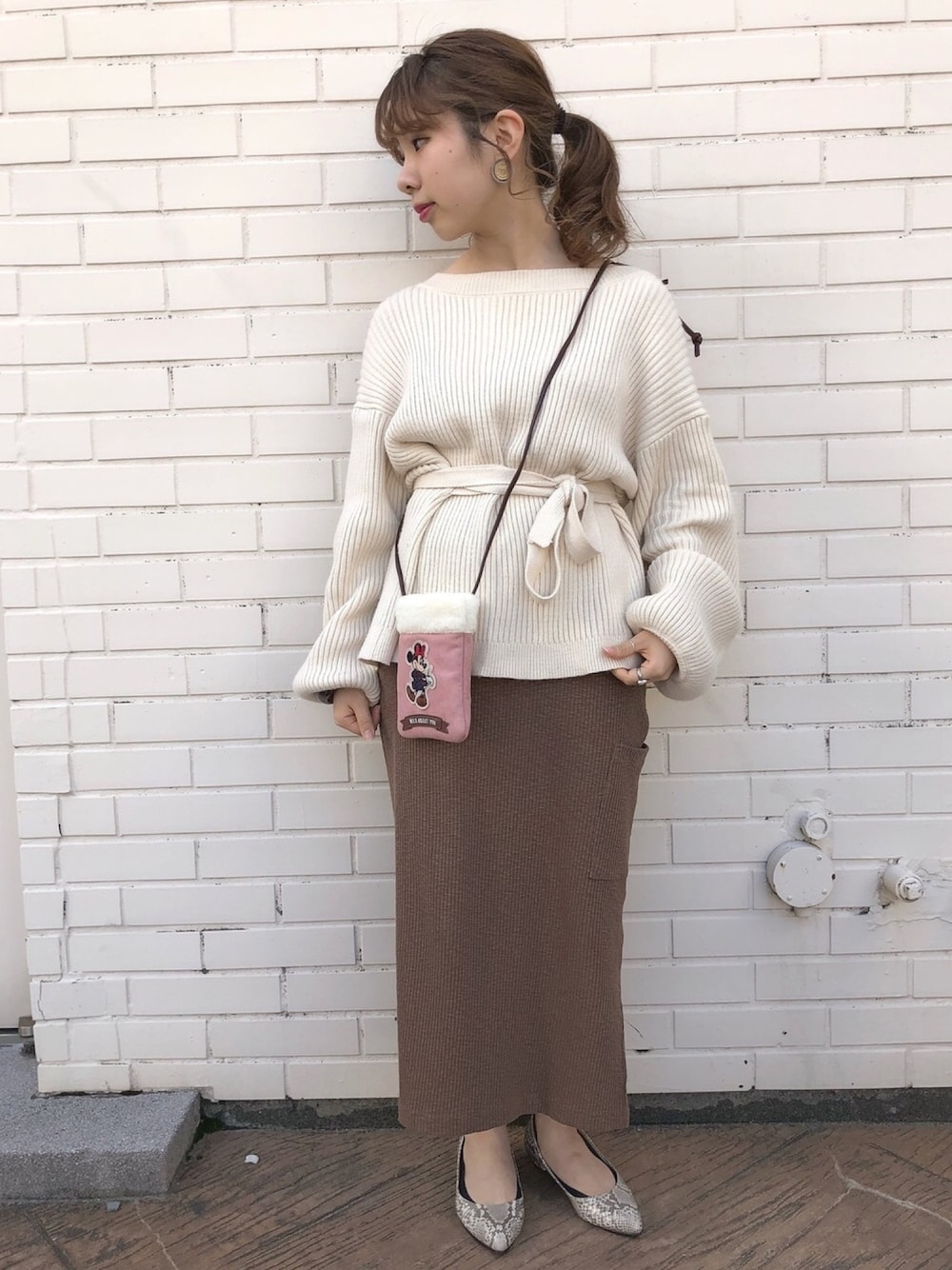 ピンク系のショルダーバッグ、グレー系のイヤリングを着用したレディースの秋コーディネートの1枚目の写真