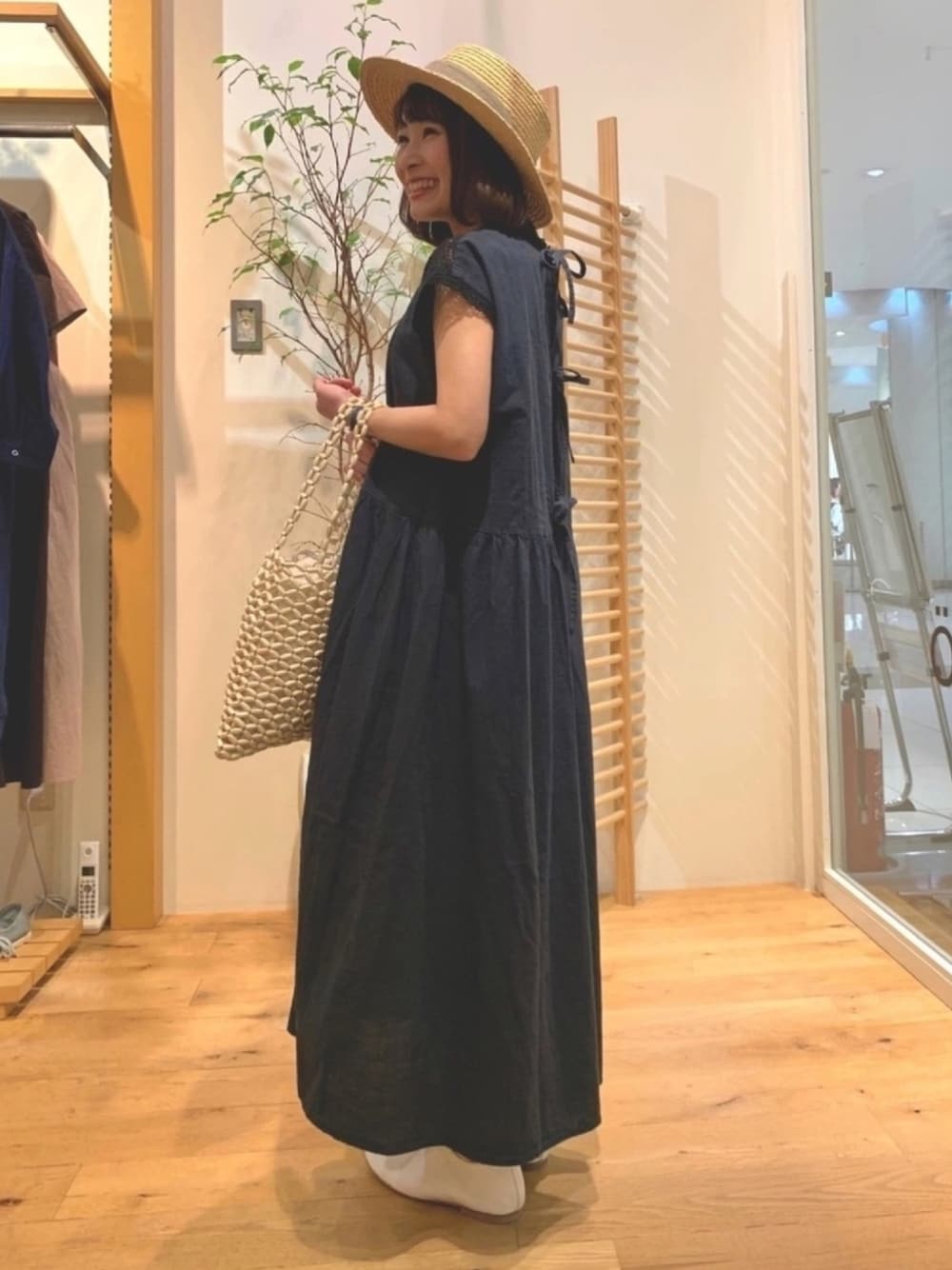 ブラック系のワンピース、ベージュ系のかごバッグ、ホワイト系のスリッポンを着用したレディースの春コーディネートの1枚目の写真