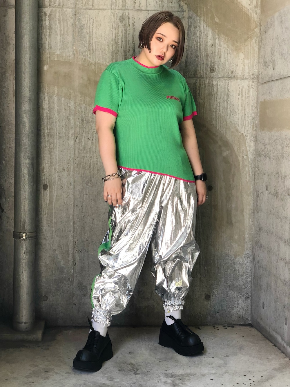 グリーン系のトップス、シルバー系のパンツを着用したレディースの夏コーディネートの1枚目の写真