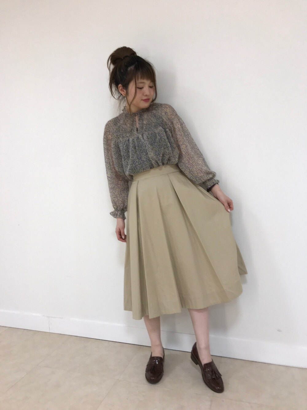 ホワイト系のシャツ/ブラウス、ベージュ系のスカート、ブラウン系のローファーを着用したレディースの春コーディネートの1枚目の写真