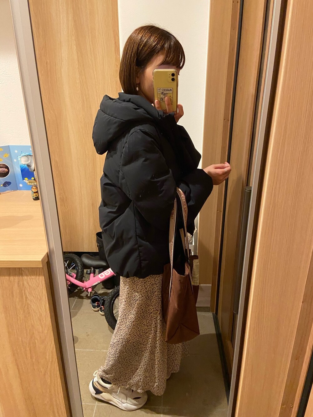 ブラック系のダウンジャケット/コート、ベージュ系のワンピース、ホワイト系のスニーカーを着用したレディースの秋コーディネートの1枚目の写真