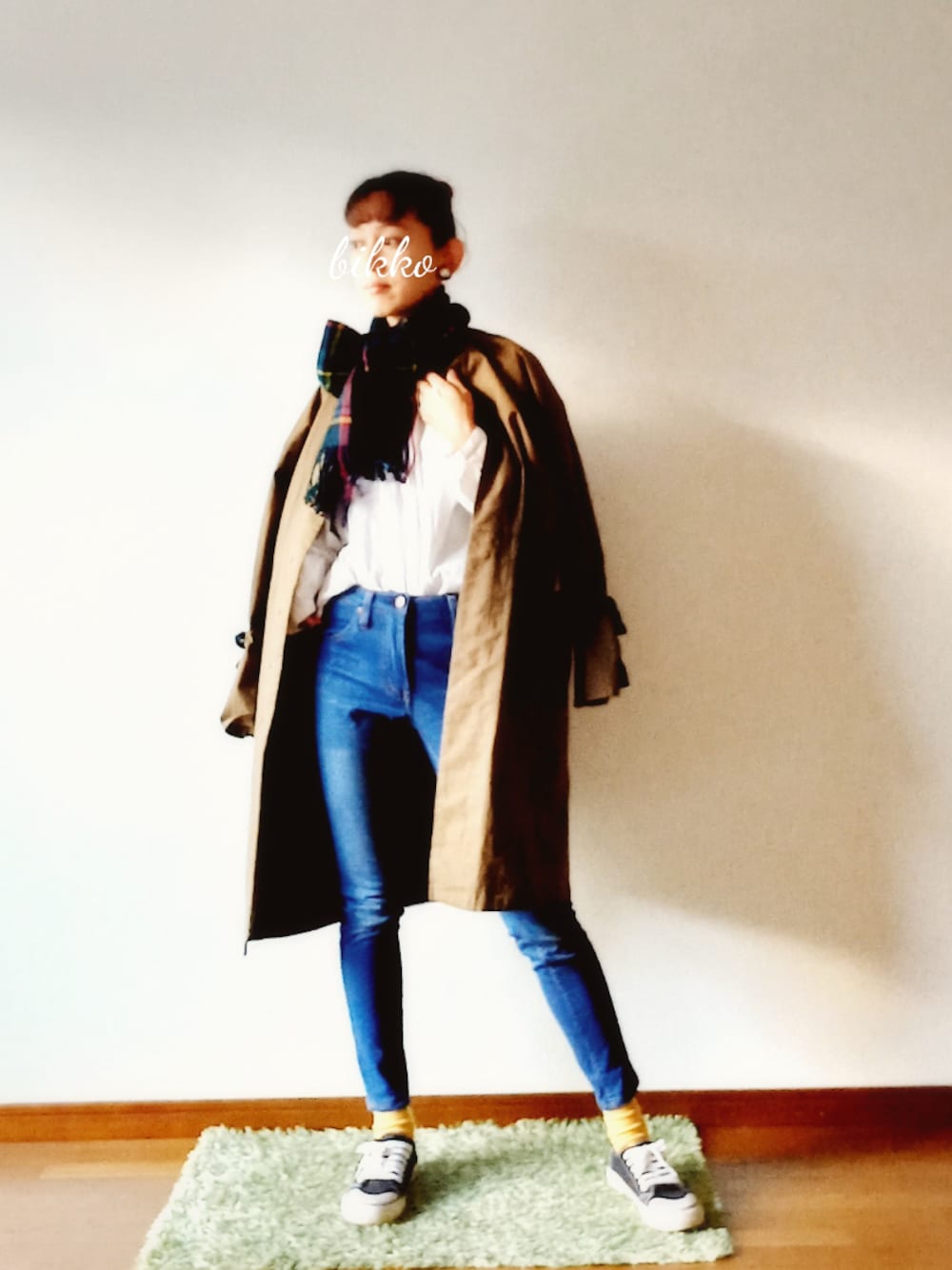 ブルー系のデニムパンツ、ブラック系のスニーカー、グリーン系のノーカラーコートを着用したレディースの冬コーディネートの1枚目の写真