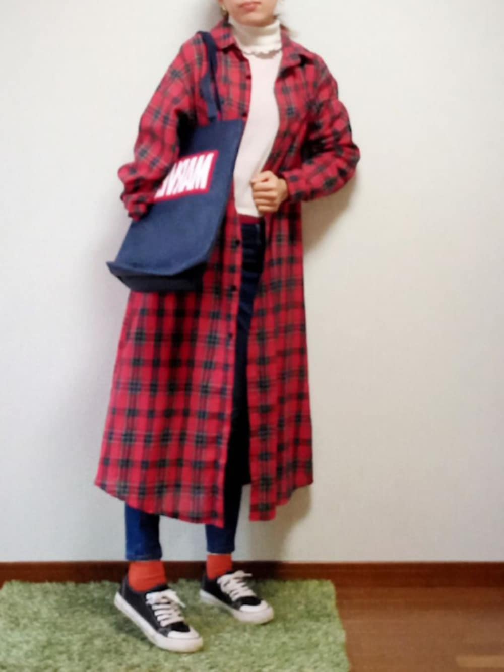 レッド系のシャツワンピース、ブルー系のトートバッグ、ブルー系のデニムパンツを着用したレディースの秋コーディネートの1枚目の写真