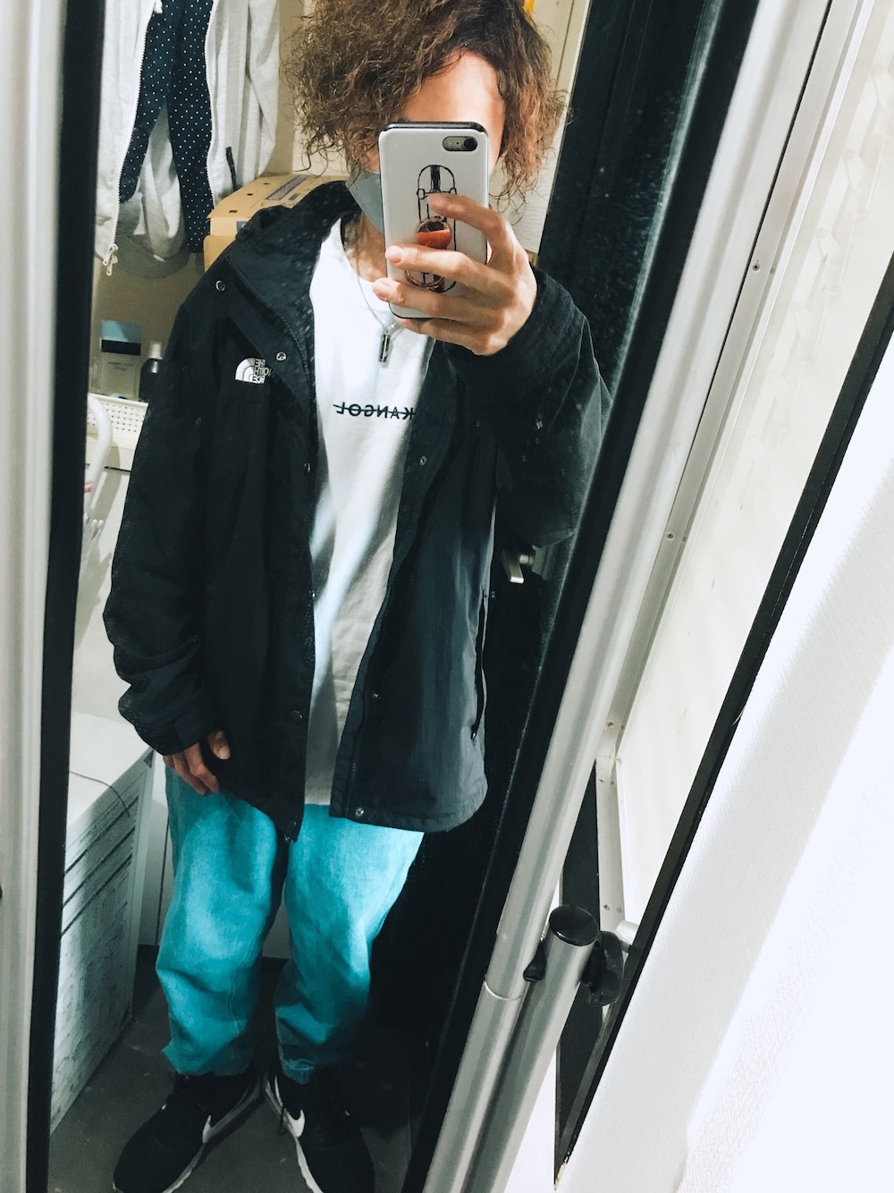 ブラック系のマウンテンパーカー、ホワイト系のTシャツ/カットソー、ブルー系のデニムパンツを着用したメンズの秋コーディネートの1枚目の写真