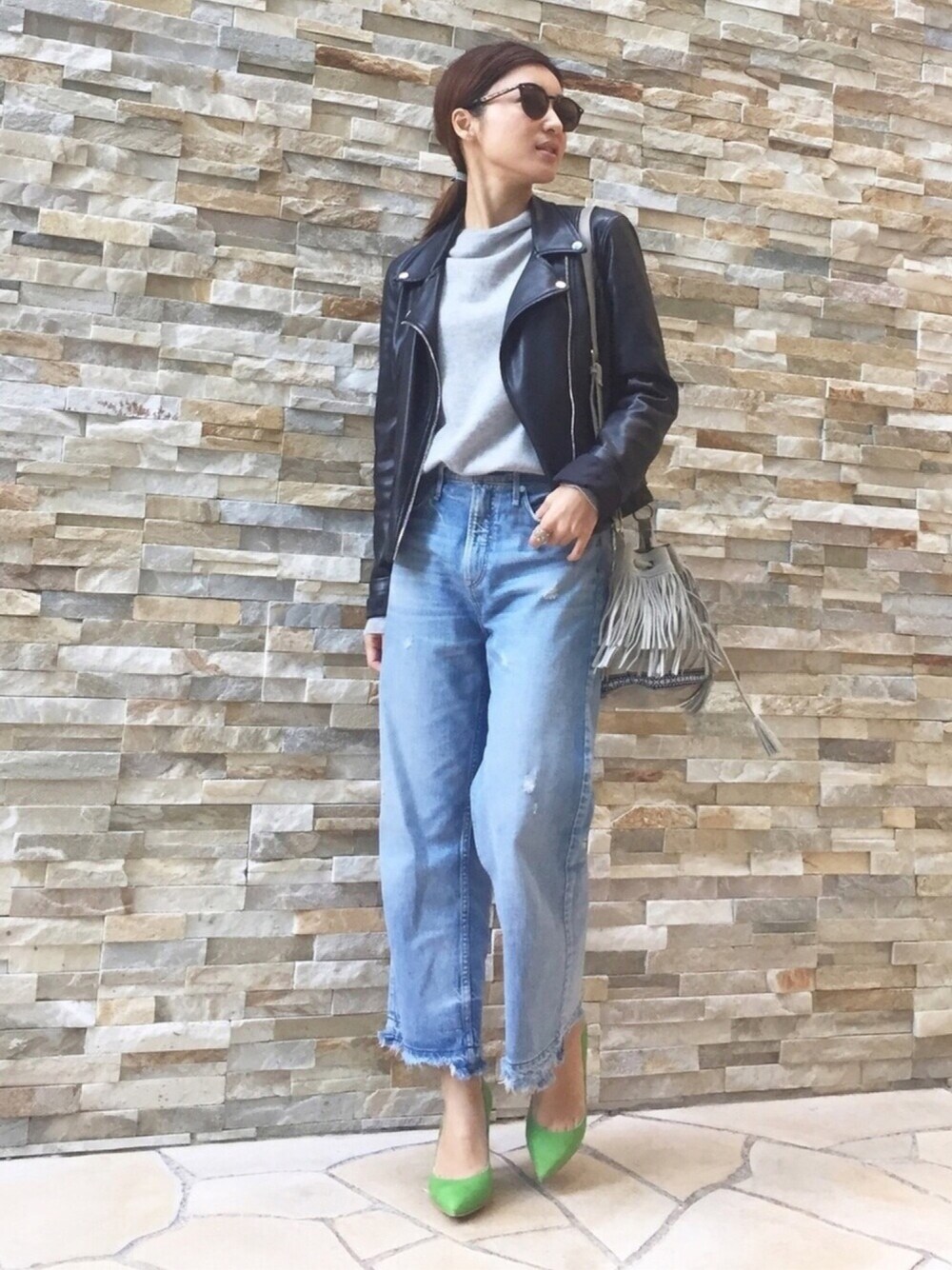 ブルー系のデニムパンツ、グリーン系のパンプス、ブラック系のライダースジャケットを着用したレディースの冬コーディネートの1枚目の写真