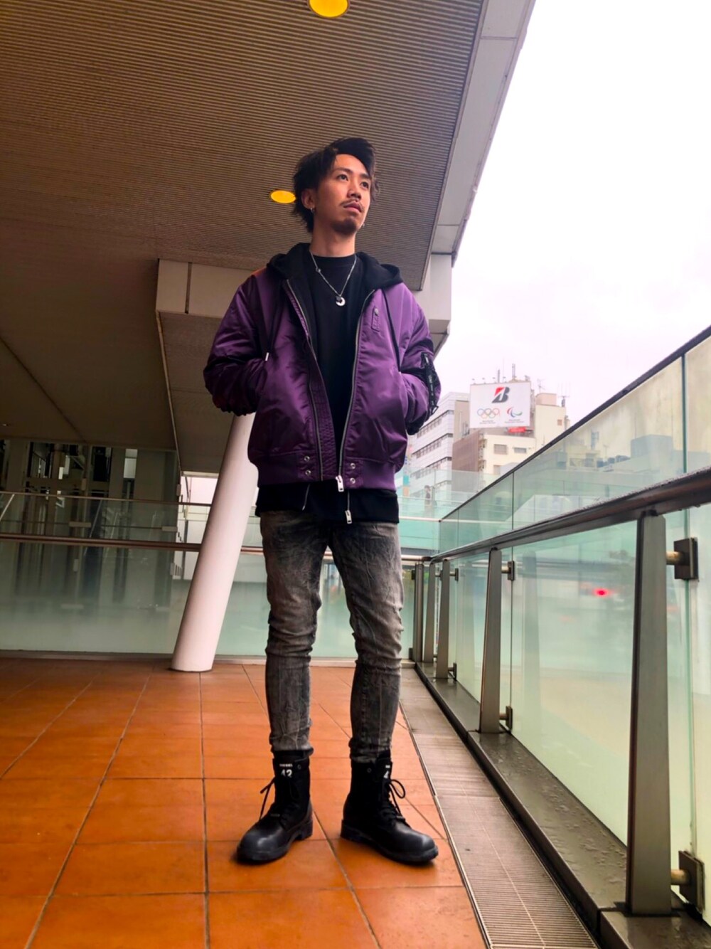 パープル系のブルゾン、ブラック系のパーカー、ブラック系のデニムパンツを着用したメンズの秋コーディネートの1枚目の写真