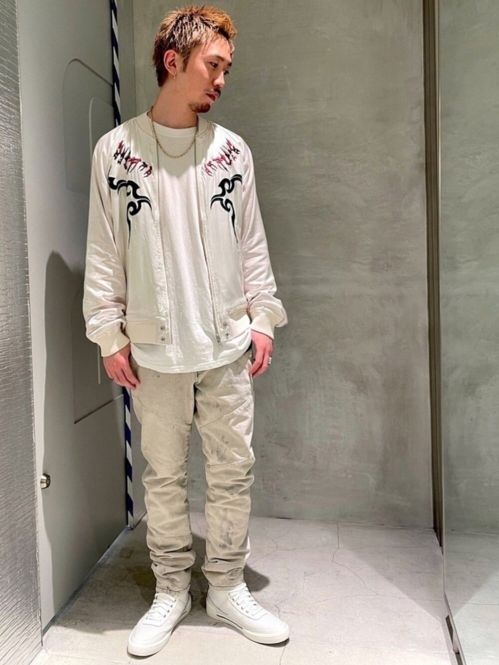 ブラック系のデニムパンツ、ホワイト系のスニーカー、ホワイト系のブルゾンを着用したメンズの春コーディネートの1枚目の写真