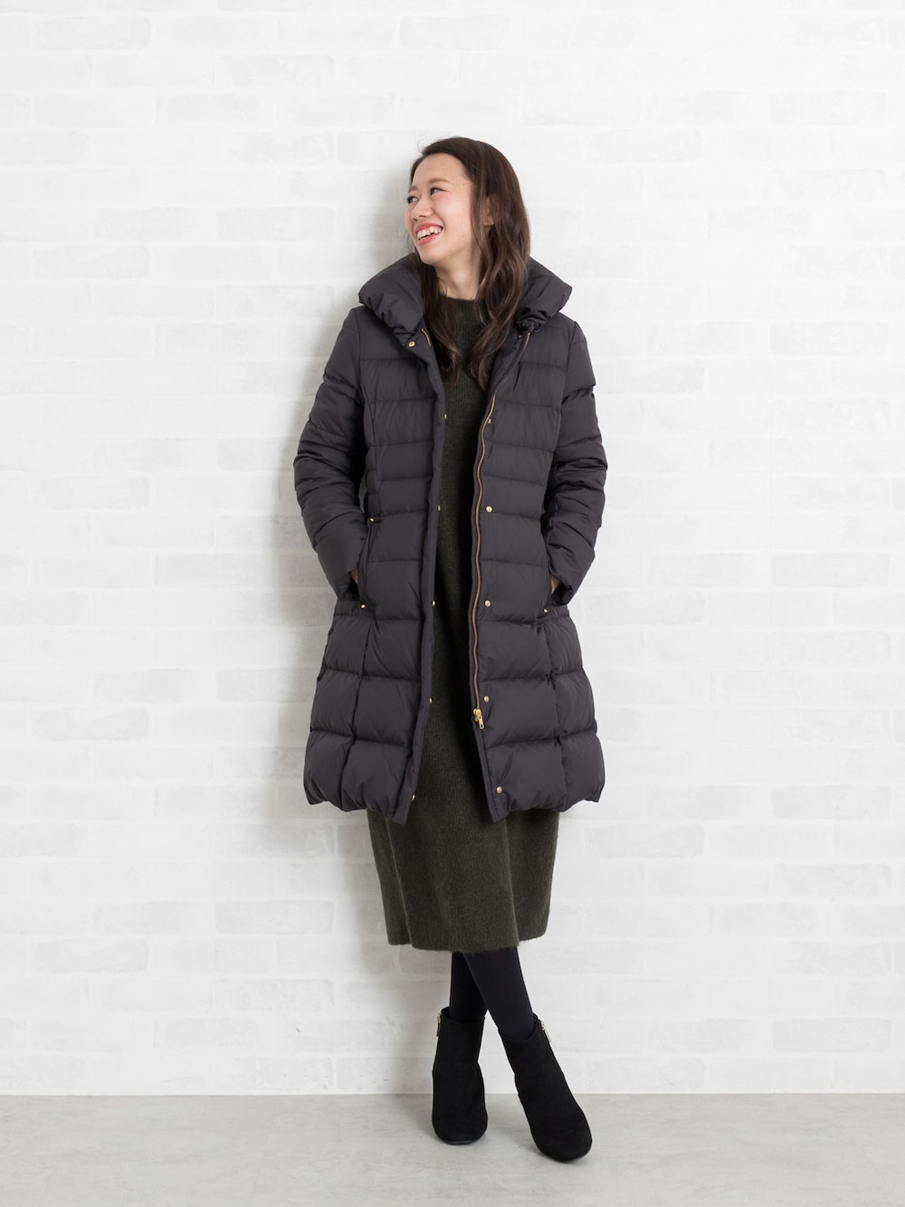 ブラック系のダウンジャケット/コート、グリーン系のワンピース、ブラック系のブーツを着用したレディースの秋コーディネートの1枚目の写真