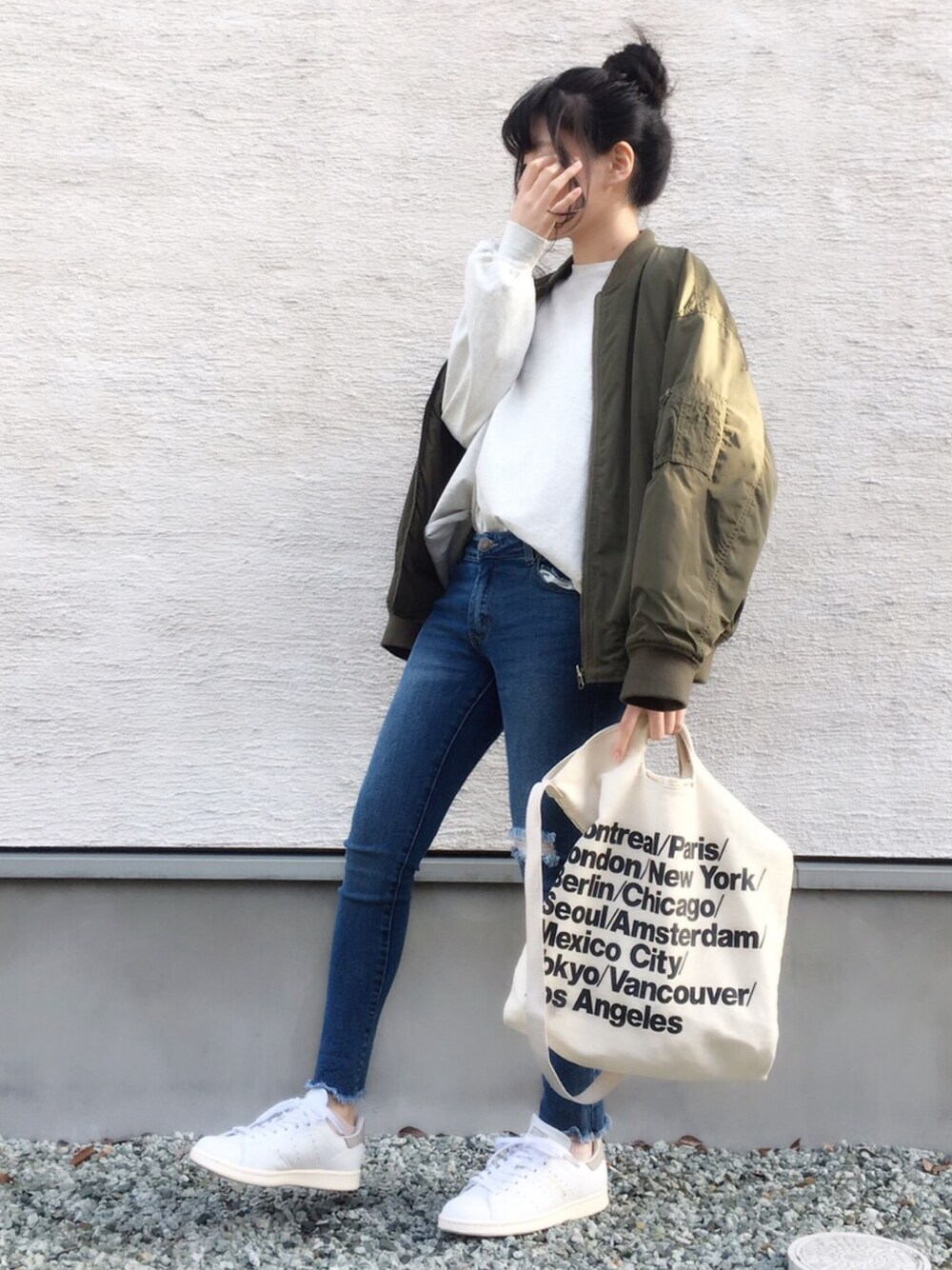 グリーン系のブルゾン、グレー系のTシャツ/カットソー、ブルー系のデニムパンツを着用したレディースの春コーディネートの1枚目の写真