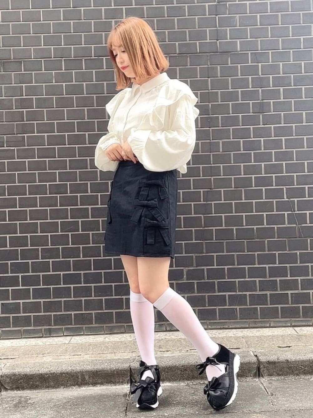 ブラック系のその他シューズ、ブラック系のスカート、ホワイト系のシャツ/ブラウスを着用したレディースの春コーディネートの1枚目の写真