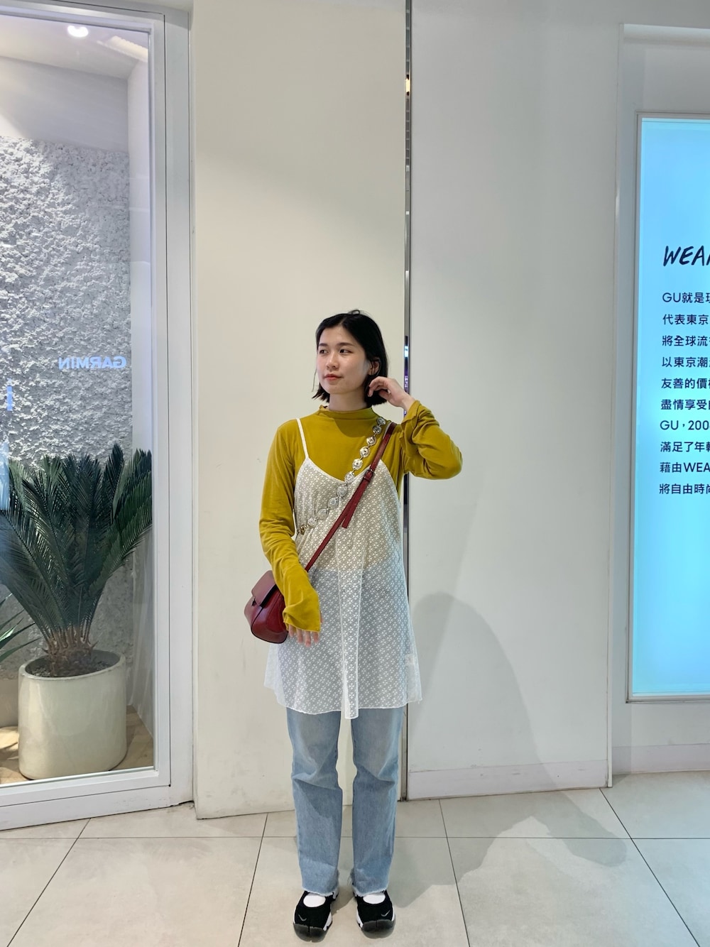 イエロー系のトップス、レッド系のショルダーバッグ、ブラック系のスニーカーを着用したレディースの春コーディネートの1枚目の写真