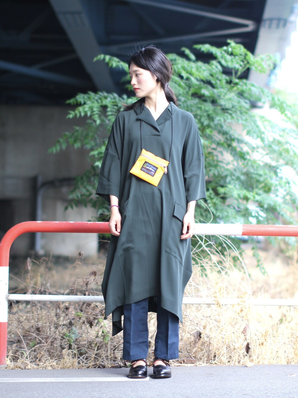 イエロー系のバッグ、グリーン系のワンピース、ブルー系のチノパンツを着用したレディースの春コーディネートの1枚目の写真