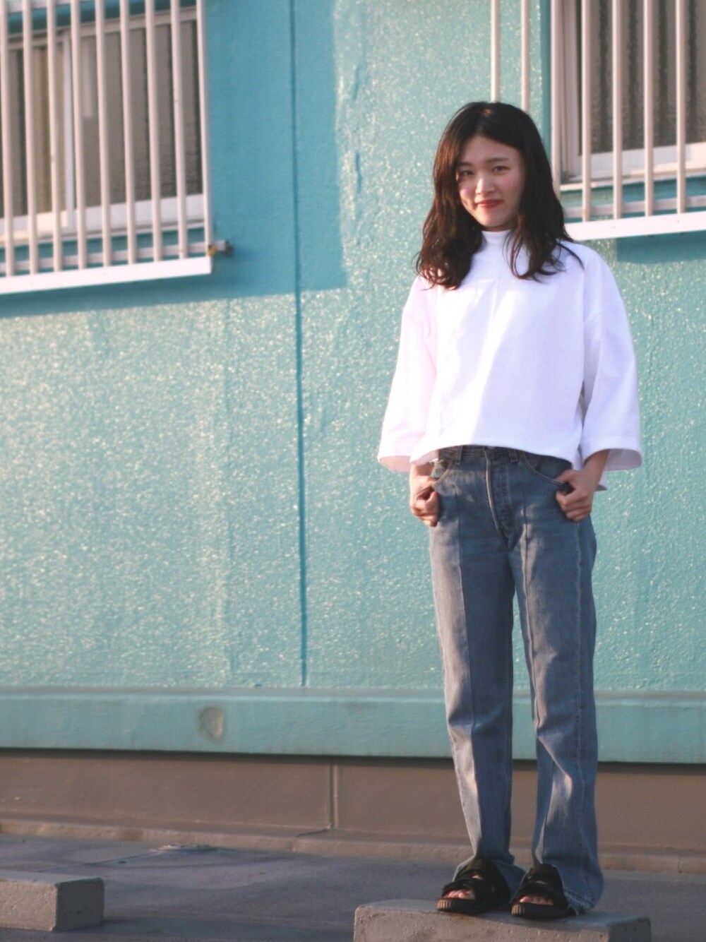 ブルー系のデニムパンツ、ホワイト系のTシャツ/カットソー、ブラック系のサンダルを着用したレディースの夏コーディネートの1枚目の写真