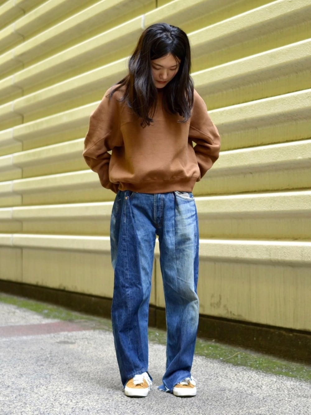 ブラウン系のトップス、ブルー系のデニムパンツ、ゴールド系のスニーカーを着用したレディースの秋コーディネートの1枚目の写真