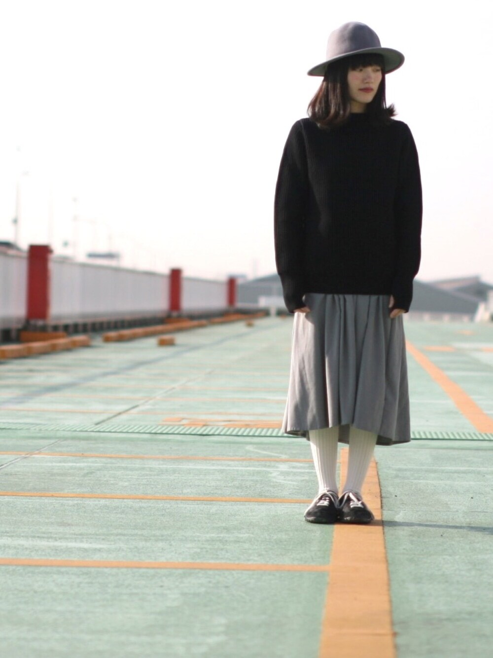 ブラック系のニット/セーター、グレー系のワンピース/ドレス、ブラック系のスニーカーを着用したレディースの秋コーディネートの1枚目の写真