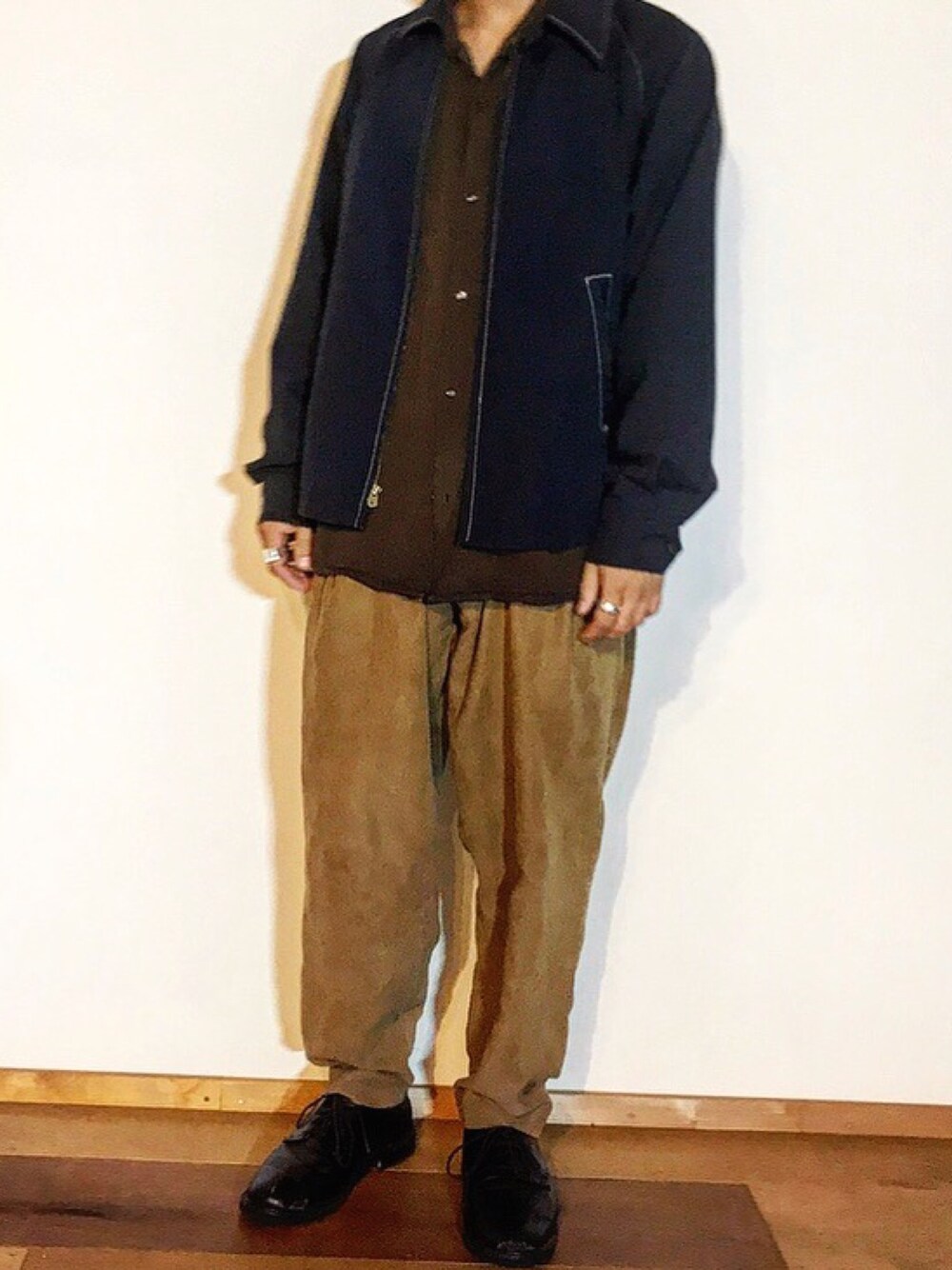 ベージュ系のスラックス、グレー系のシャツ/ブラウス、ブラック系のドレスシューズを着用したメンズの秋コーディネートの1枚目の写真