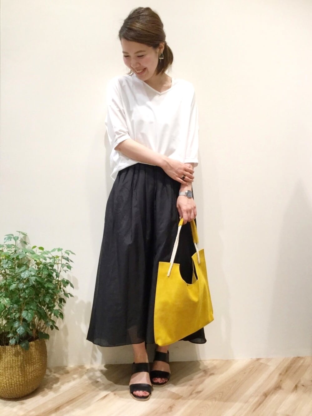 ブラック系のスカート、ホワイト系のTシャツ/カットソー、ブラック系のサンダルを着用したレディースの夏コーディネートの1枚目の写真