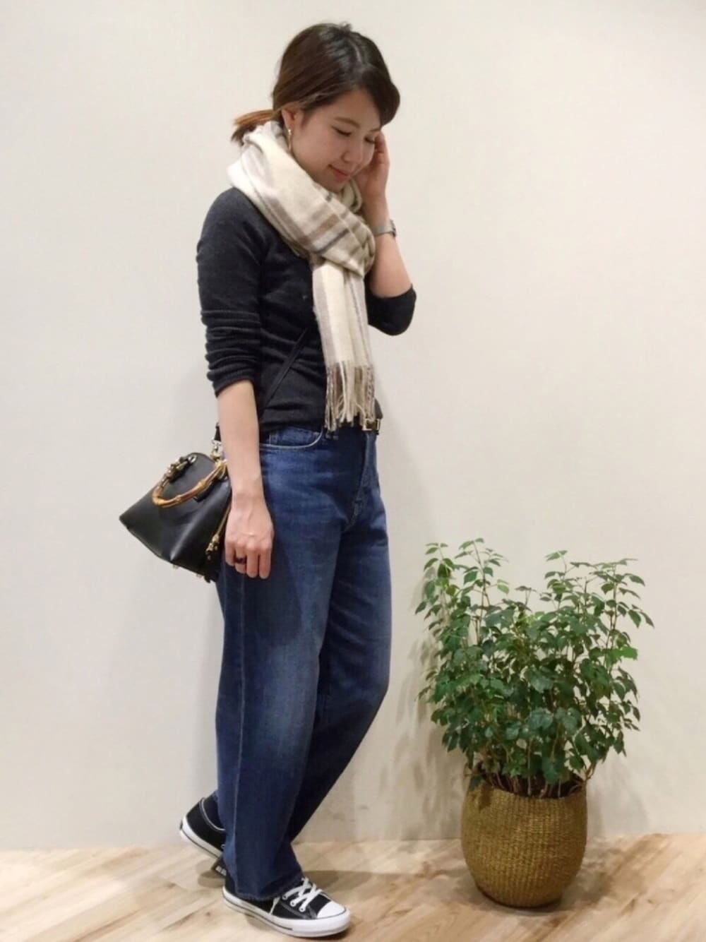 グレー系のニット/セーター、ブルー系のデニムパンツ、ブラック系のショルダーバッグを着用したレディースの秋コーディネートの1枚目の写真