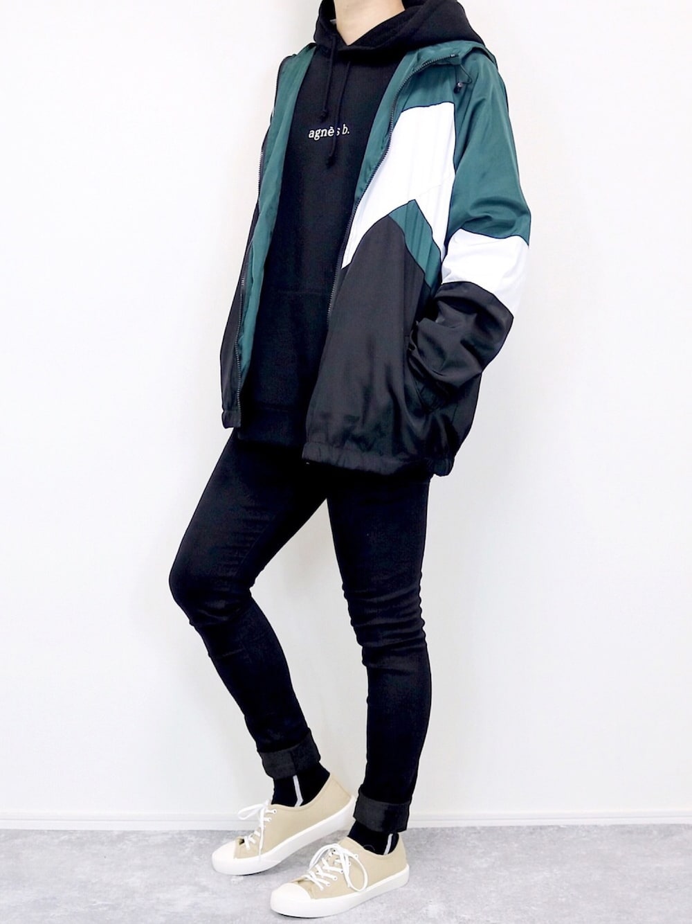 グリーン系のブルゾン、ブラック系のパーカー、ブラック系のデニムパンツを着用したメンズの冬コーディネートの1枚目の写真