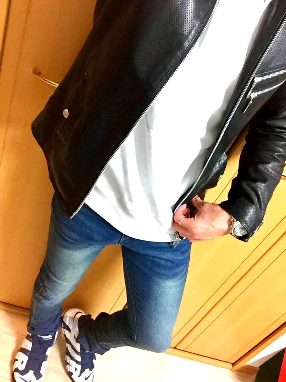 ブラック系のライダースジャケット、ブルー系のデニムパンツ、ブルー系のスニーカーを着用したメンズの冬コーディネートの1枚目の写真