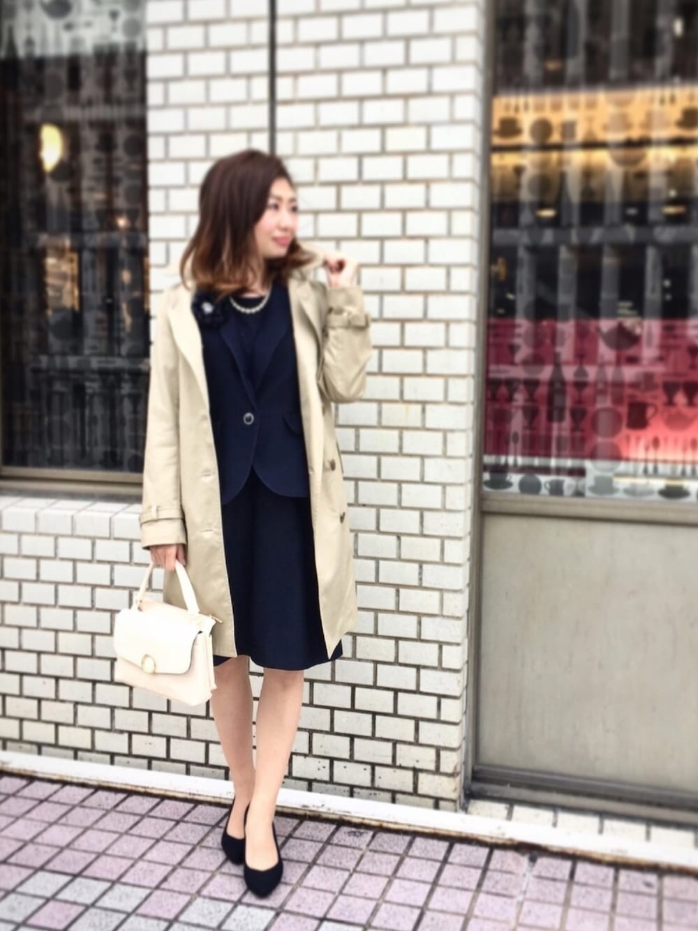 ブルー系のテーラードジャケット、ブルー系のワンピース、ベージュ系のトレンチコートを着用したレディースの冬コーディネートの1枚目の写真