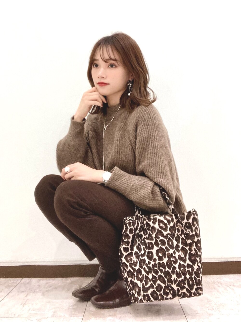 ブラック系のその他パンツ、ブラウン系のニット/セーター、ブラウン系のショルダーバッグを着用したレディースの冬コーディネートの1枚目の写真
