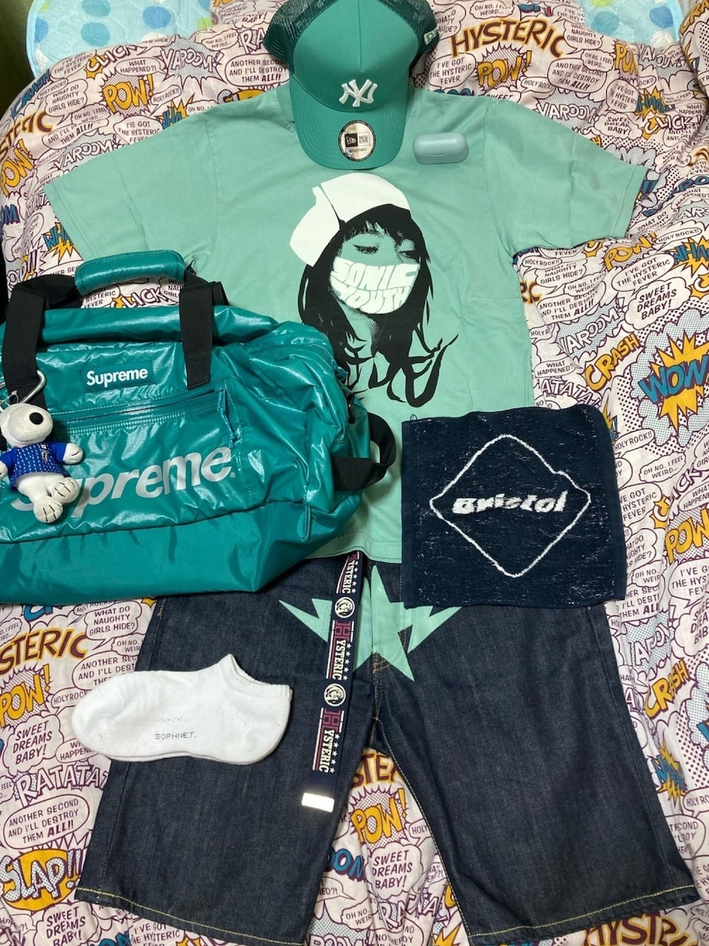 グリーン系のTシャツ/カットソー、グリーン系のドラムバッグ、ブルー系のデニムパンツを着用したメンズの夏コーディネートの1枚目の写真