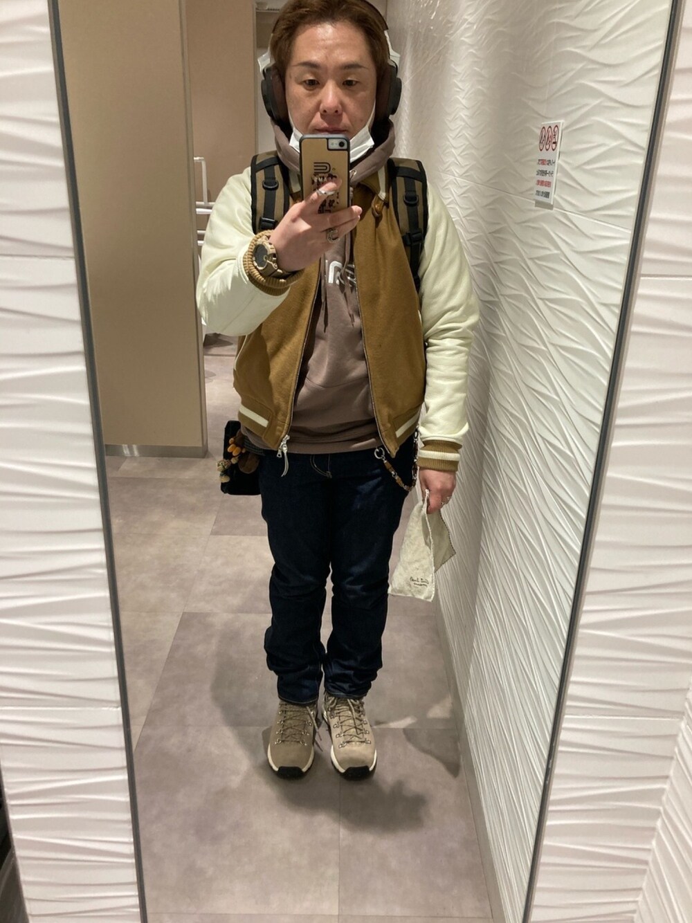 ブラウン系のスタジャン、ブラウン系のTシャツ/カットソー、ベージュ系のバックパック/リュックを着用したメンズの冬コーディネートの1枚目の写真