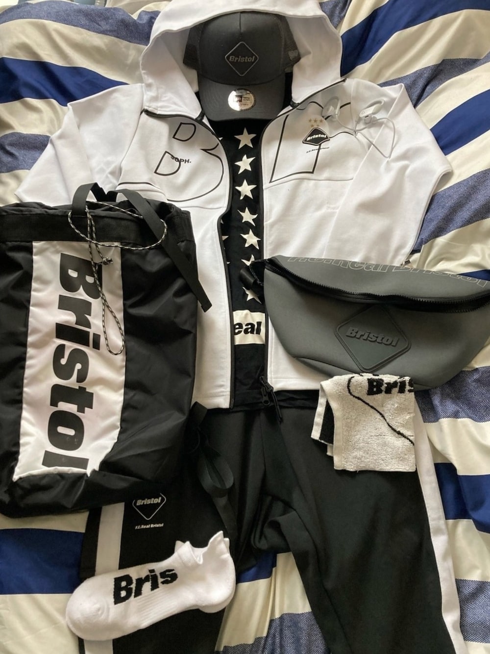 ホワイト系のパーカー、ブラック系のTシャツ/カットソー、ブラック系のバックパック/リュックを着用したメンズの春コーディネートの1枚目の写真